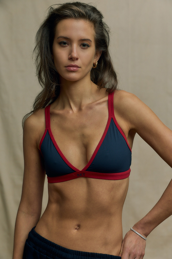 Coach is posing in a blue swimming suit with a touch of red.